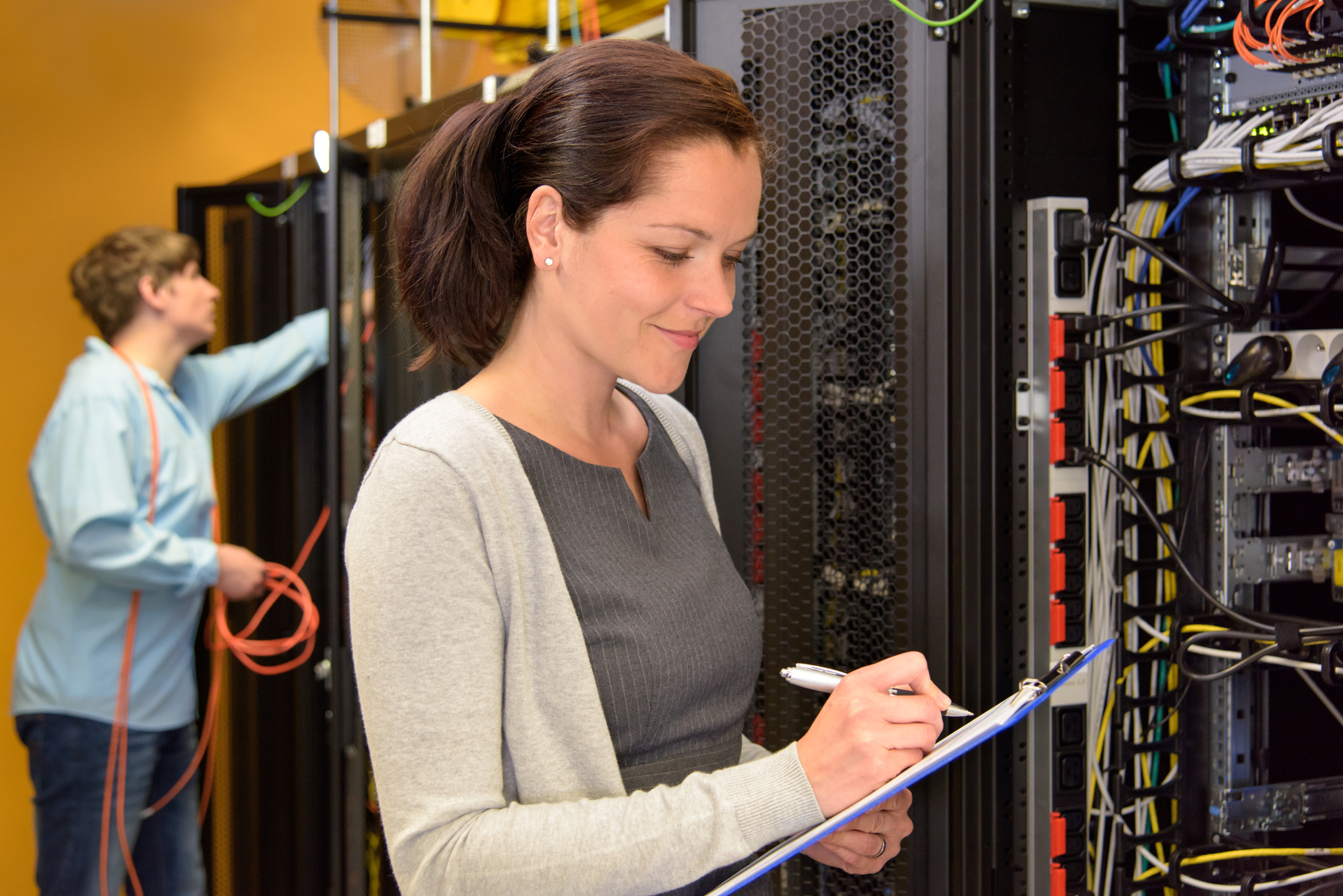 Woman IT engineer in server room checking network