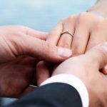 closeup-groom-putting-ring-finger-bride-lights